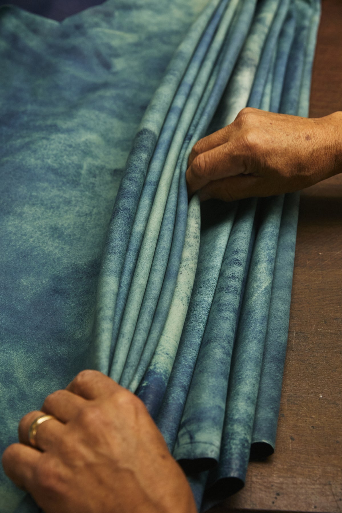 Image of hands leafing through pieces of folded leather.