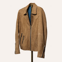 The Legend suede jacket in a rich, neutral tone, featuring a slim tailored fit, subtle western shoulder yoke, three exterior zippered pockets, and adjustable sleeve gussets. Made from lightweight, malleable calf suede designed for timeless style and durability.