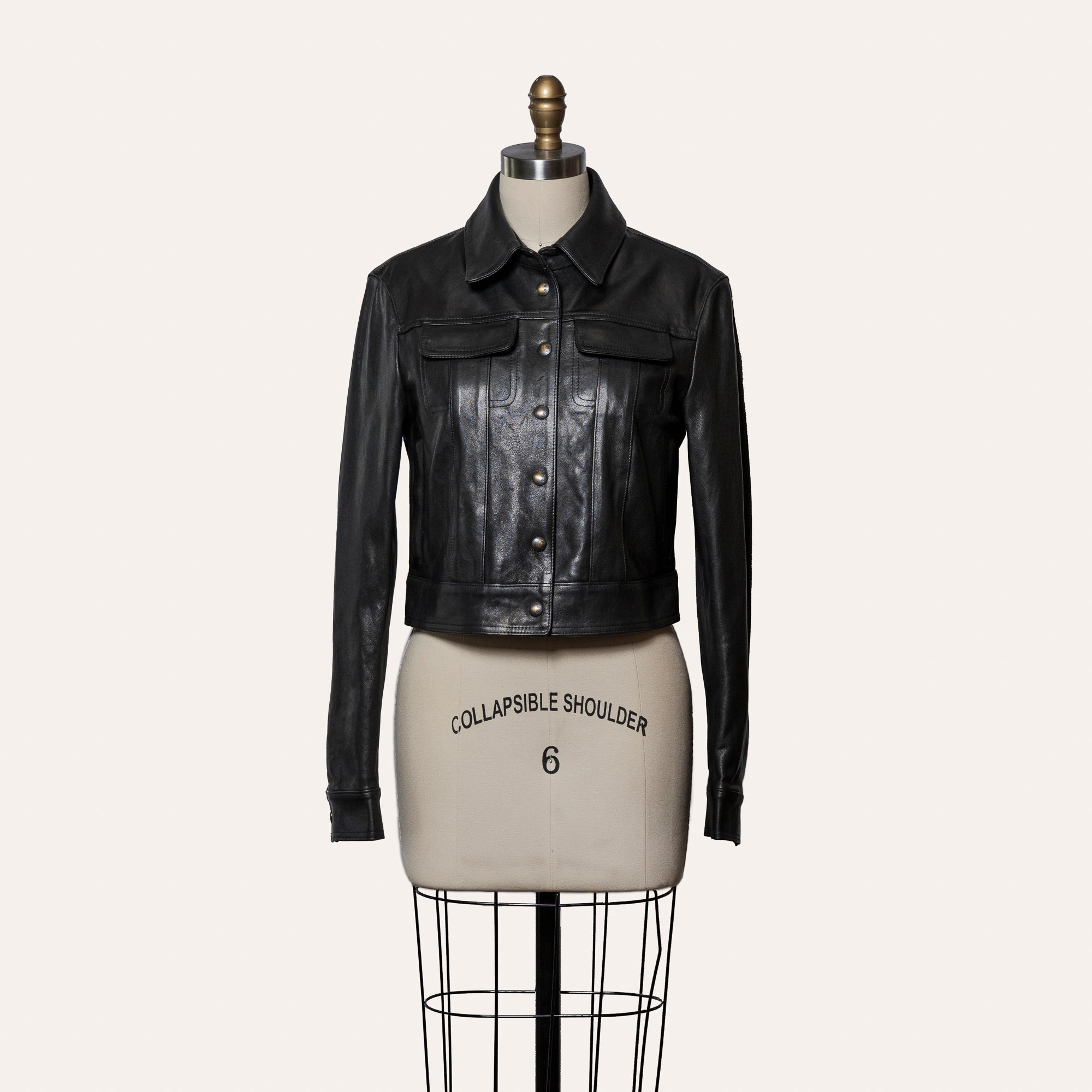 Black leather jacket on a mannequin with 'Collapsible Shoulder' label against a white background