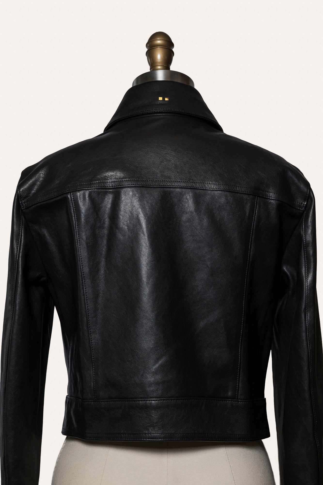 Black leather jacket on a mannequin against a white background