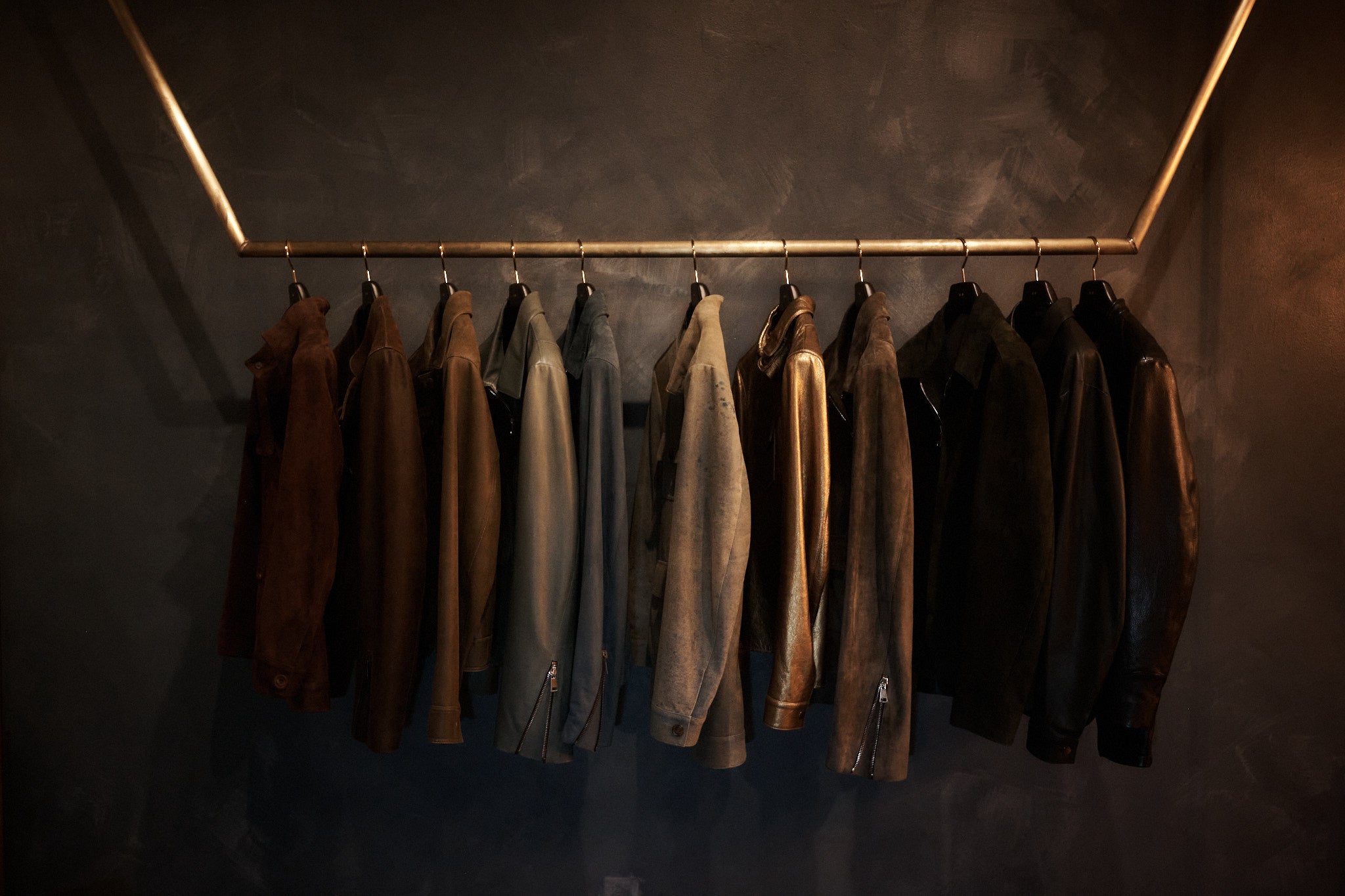 Row of jackets hanging on a rack against a dark wall