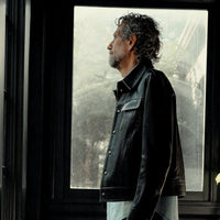  The '68 black calf leather trucker jacket on model in profile, tailored silhouette and snap front. Handmade in Italy