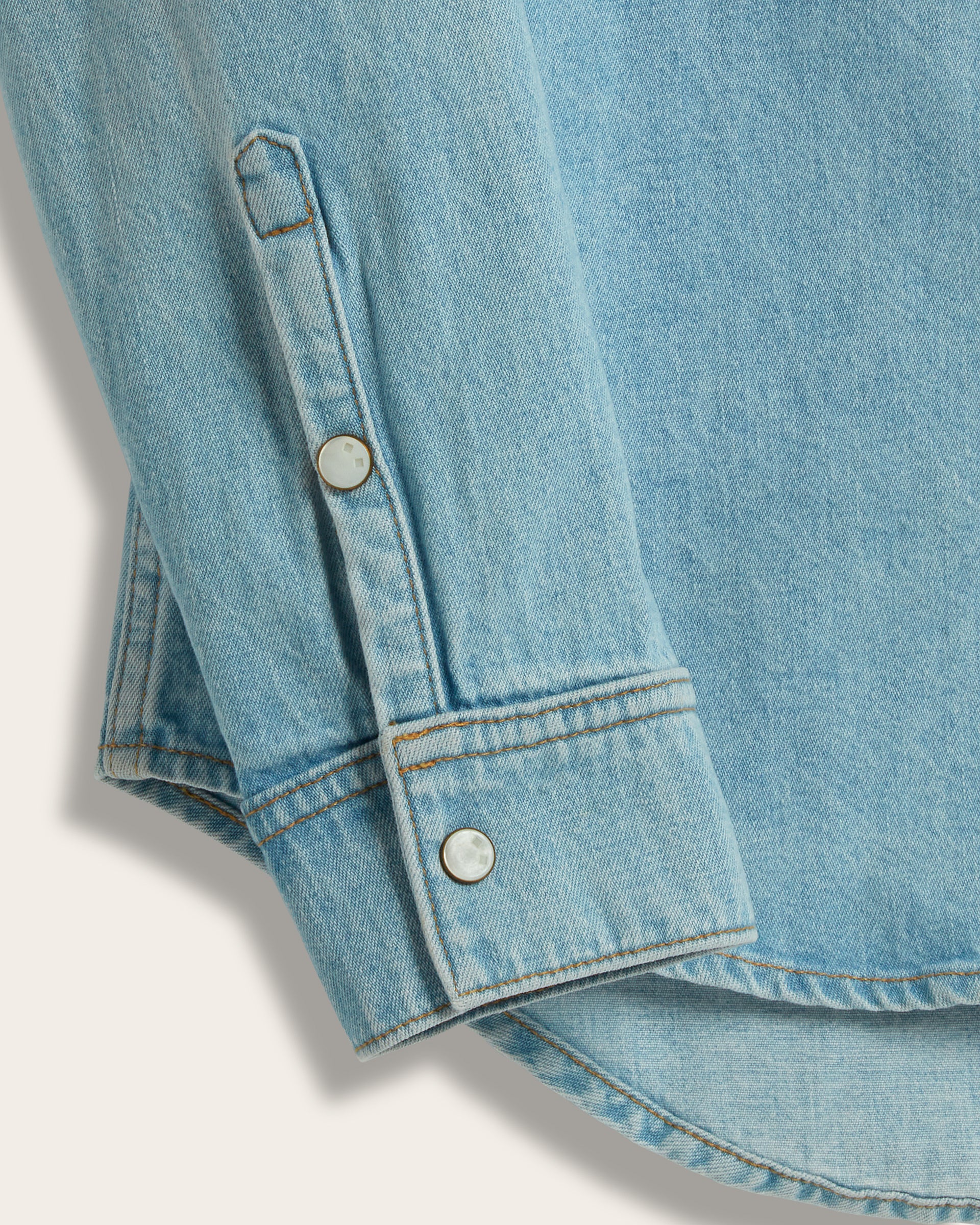 Close-up of The Allen denim shirt sleeve showing pearl snap button on cuff and cuff seam 