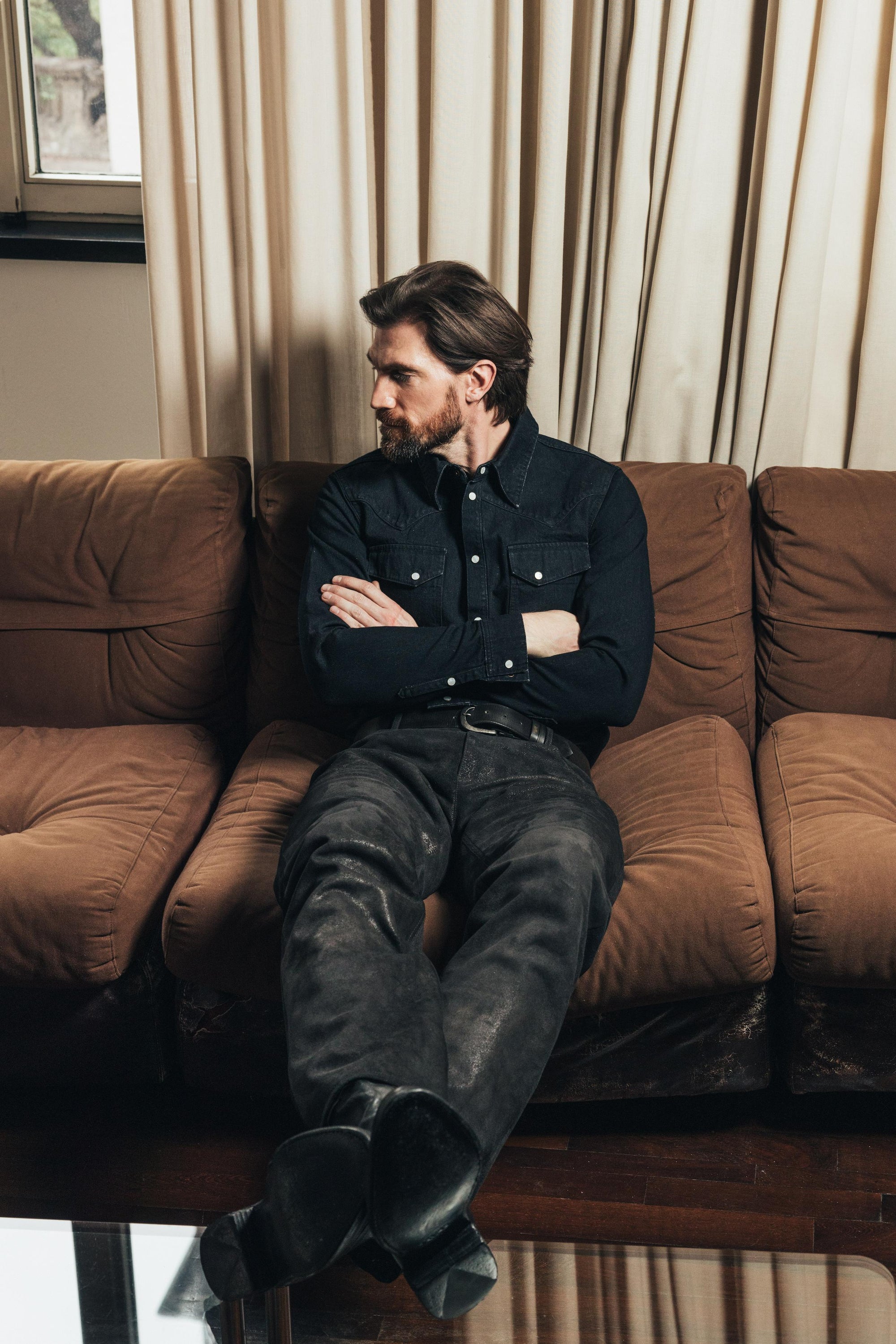 Model on couch wears Savas Allen Denim shirt in black. Selvedge Denim.  Handmade in LA.