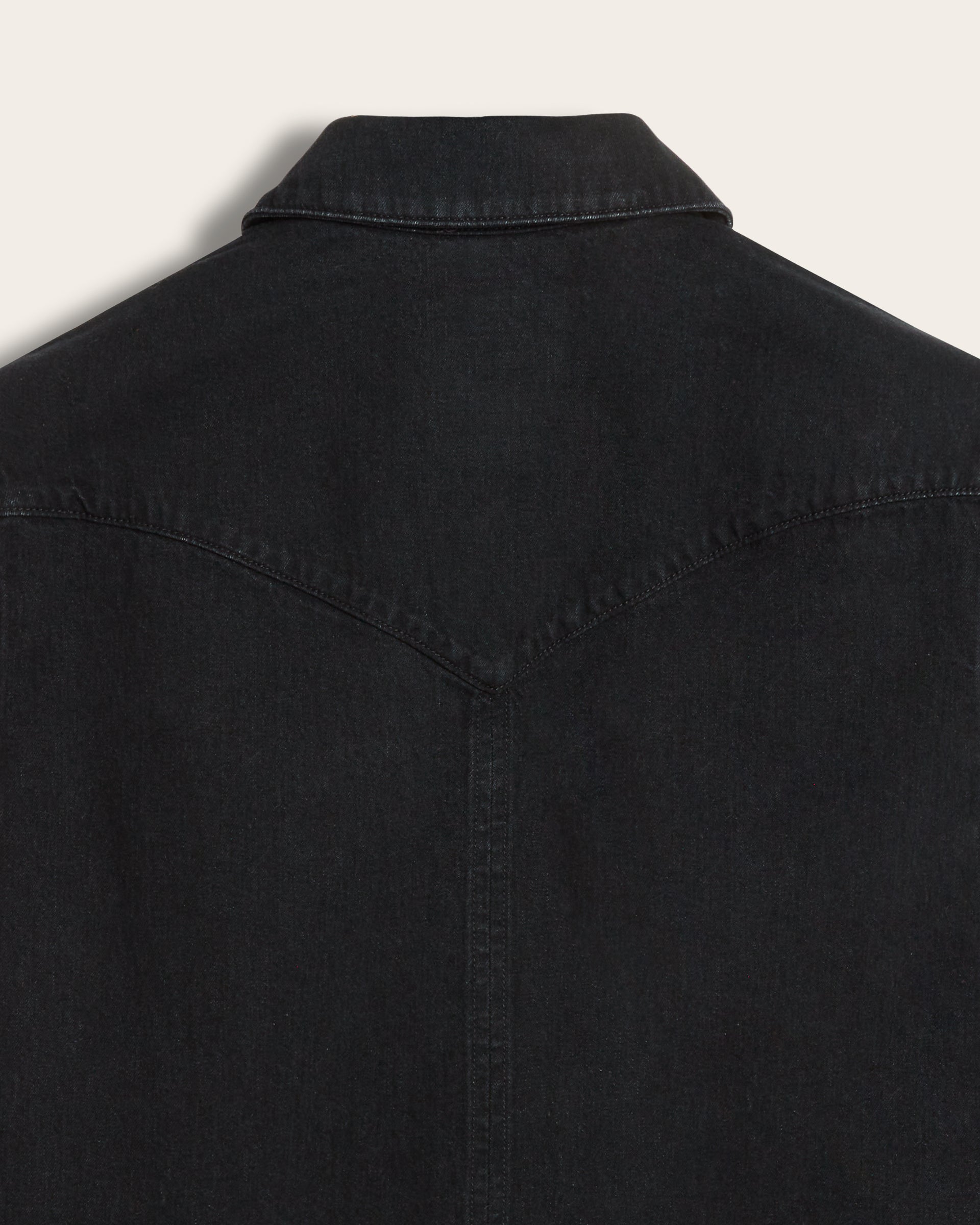 Close-up of the back of black western style denim shirt jacket, showing the collar and back yoke seam
