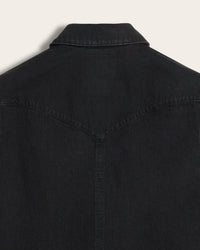Close-up of the back of black western style denim shirt jacket, showing the collar and back yoke seam