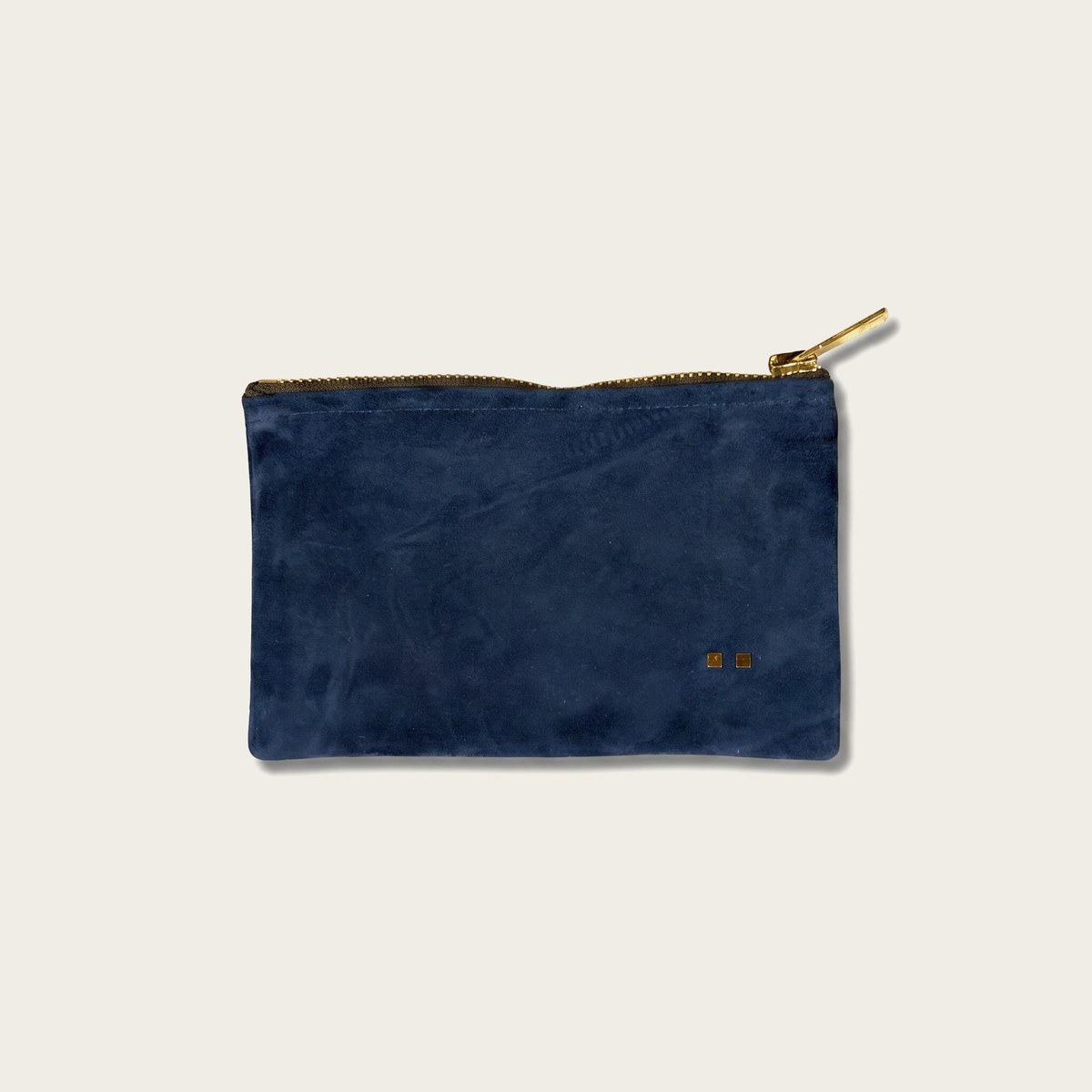 Blue suede pouch with gold zipper on a light gray background