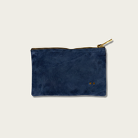 Blue suede pouch with gold zipper on a light gray background