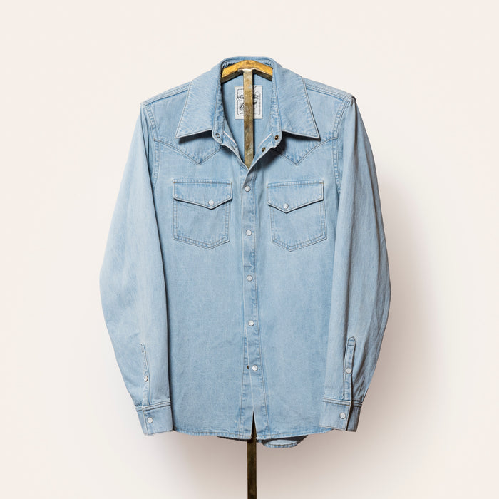 Light blue denim shirt on a hanger against a white background