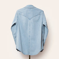 Light blue denim shirt on a hanger against a white background