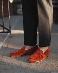 The Coyle saffron suede loafer worn with tailored dark trousers, Two Dots brass rivets visible at vamp
