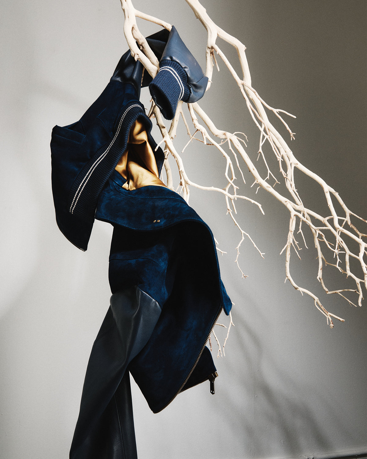 Navy blue jacket draped over a branch against a neutral background