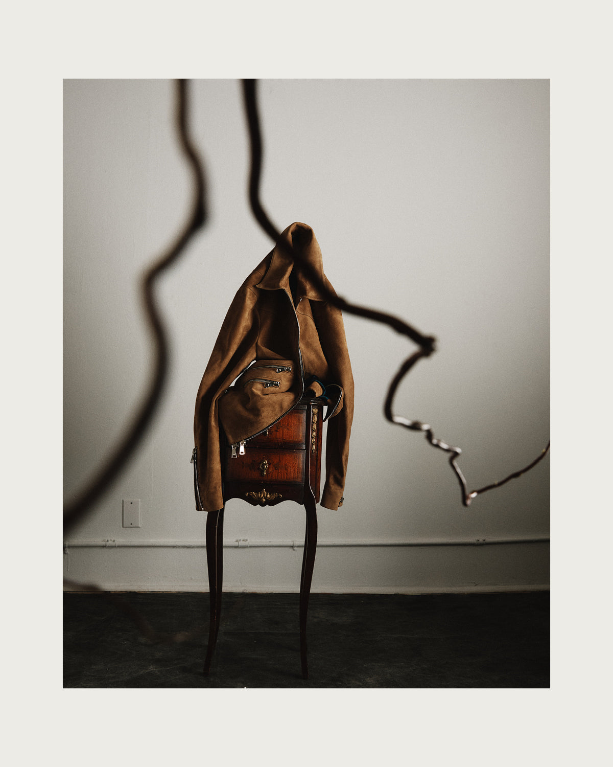 Brown leather jacket on a stand against a plain wall