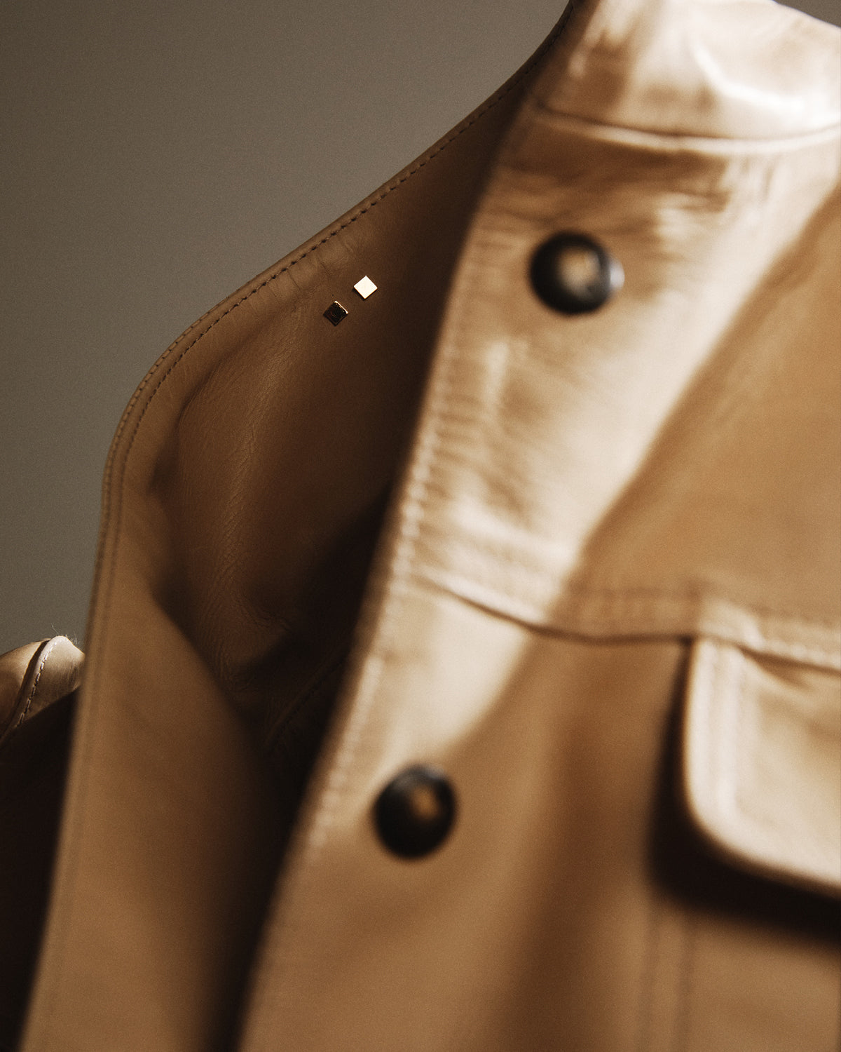 Close-up of a beige jacket with black buttons on a neutral background