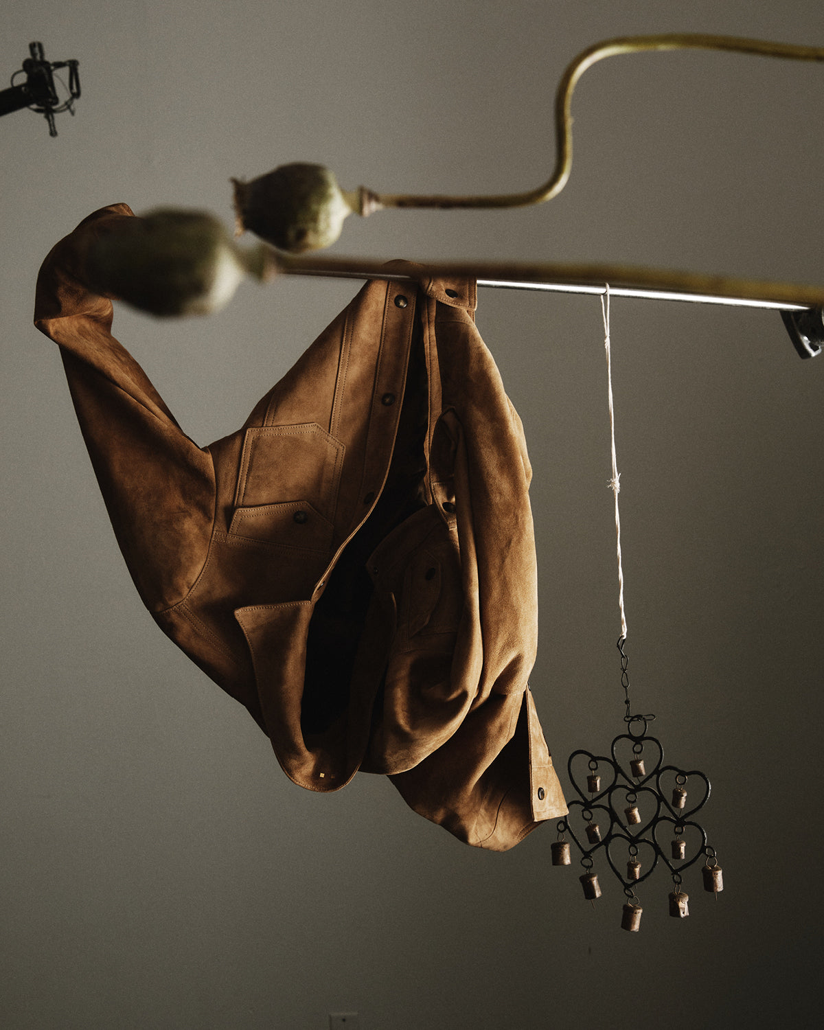 Brown jacket hanging on a hook with a decorative heart-shaped object against a dark background