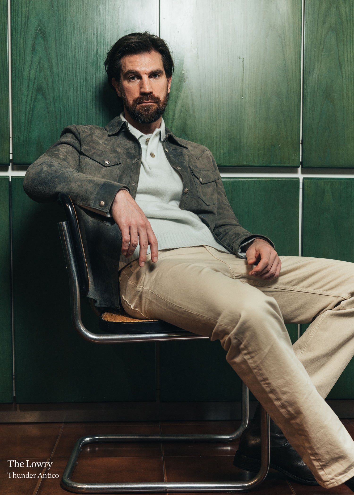 Man sitting on a chair against a green tiled wall