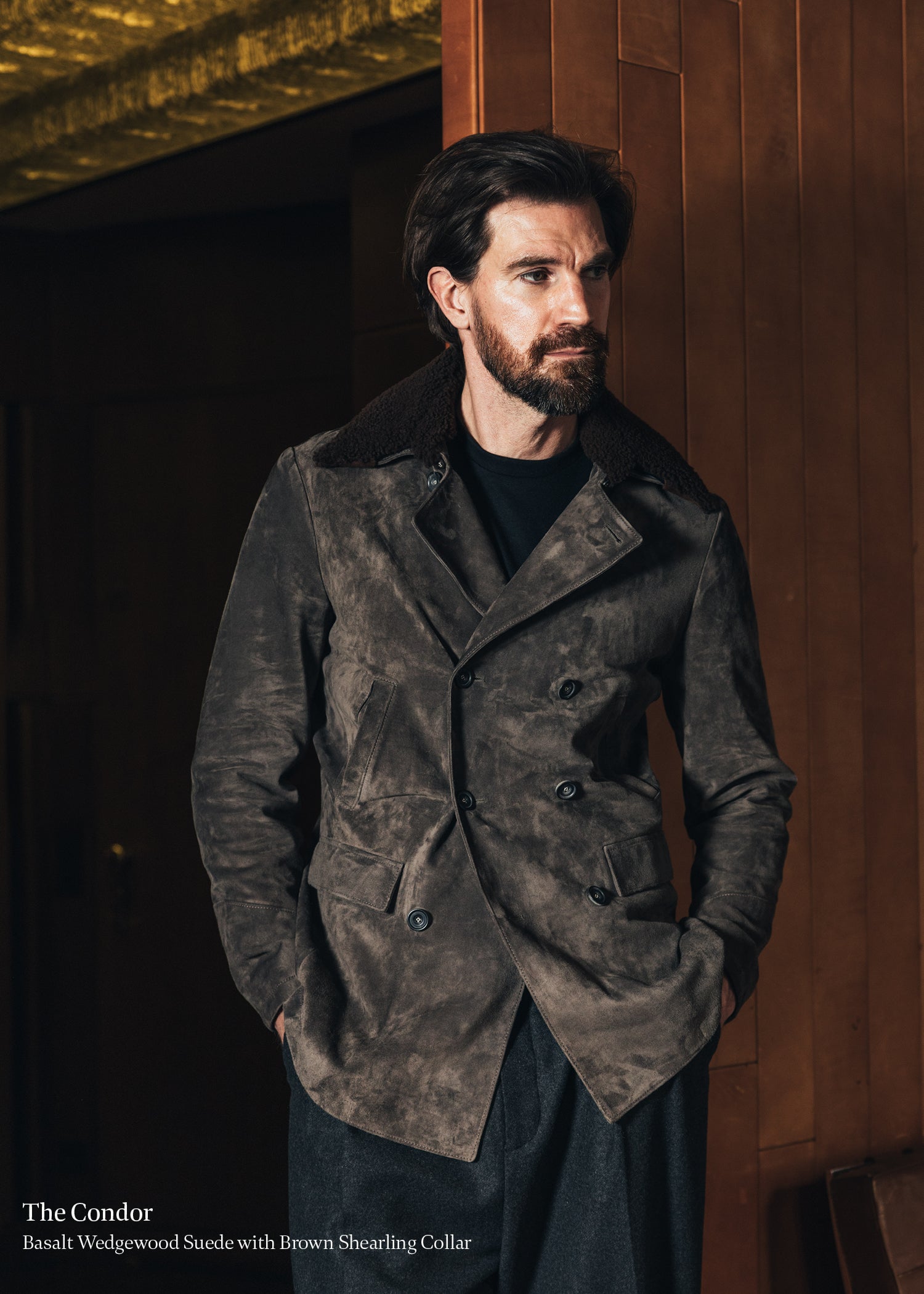 Man wearing a brown suede coat with a fur collar indoors