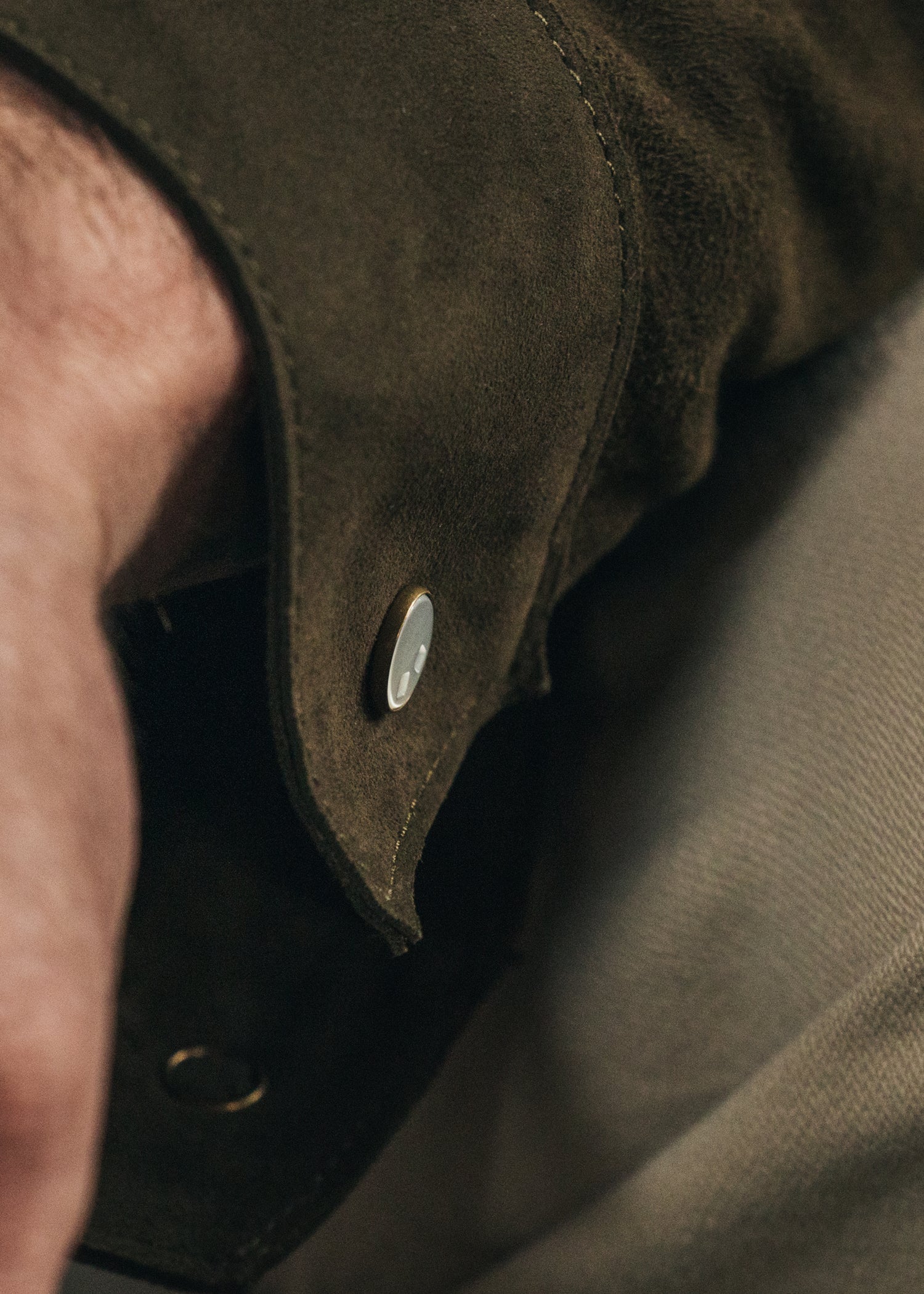 Close-up of a brown leather jacket with a button on a blurred background