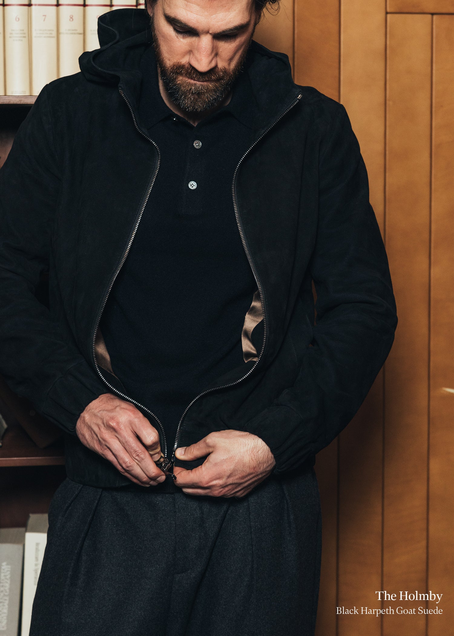 Man wearing a black coat with a wooden panel background
