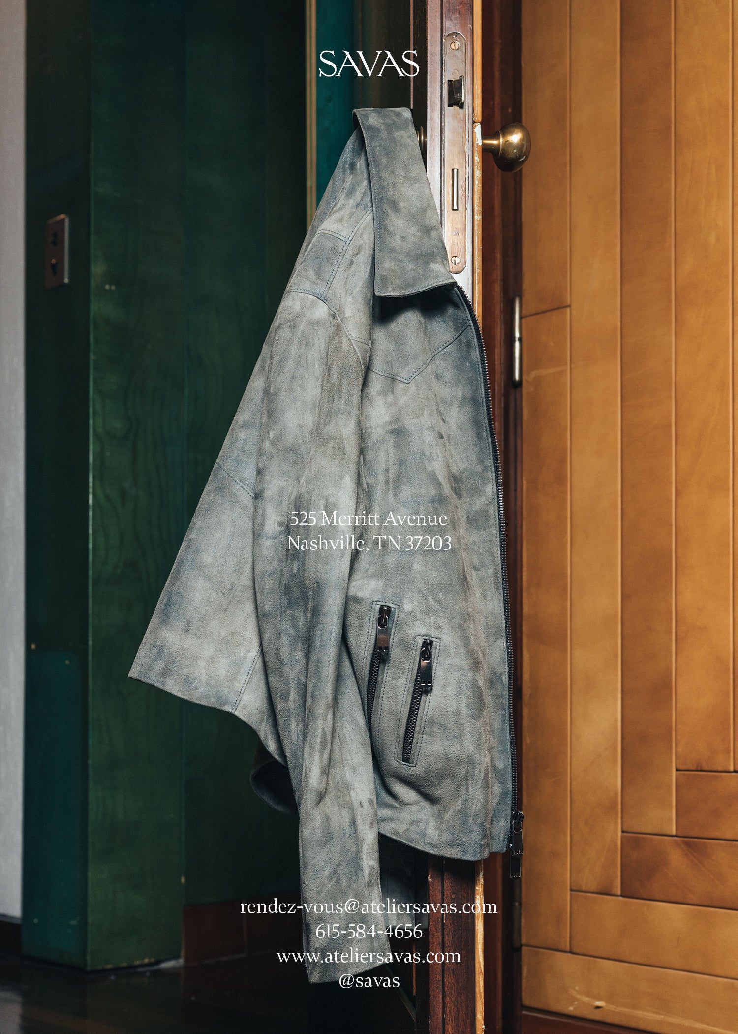 Gray suede jacket hanging on a door with Savas branding. 525 Merritt Ave. Nashville, TN 37203 rendez-vous@ateliersavas.com 615-584-4656 www.ateliersavas.com @savas