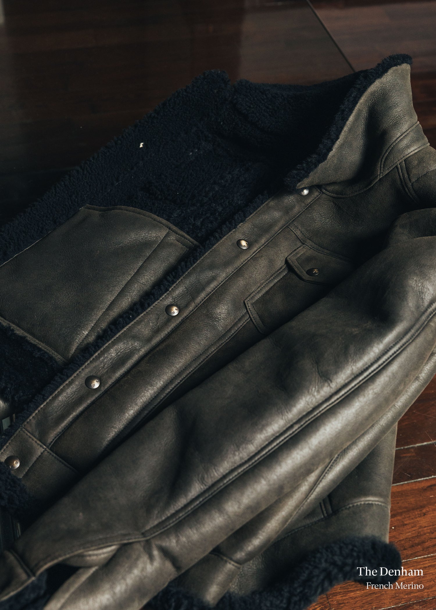 Black leather jacket with fur lining on a wooden surface