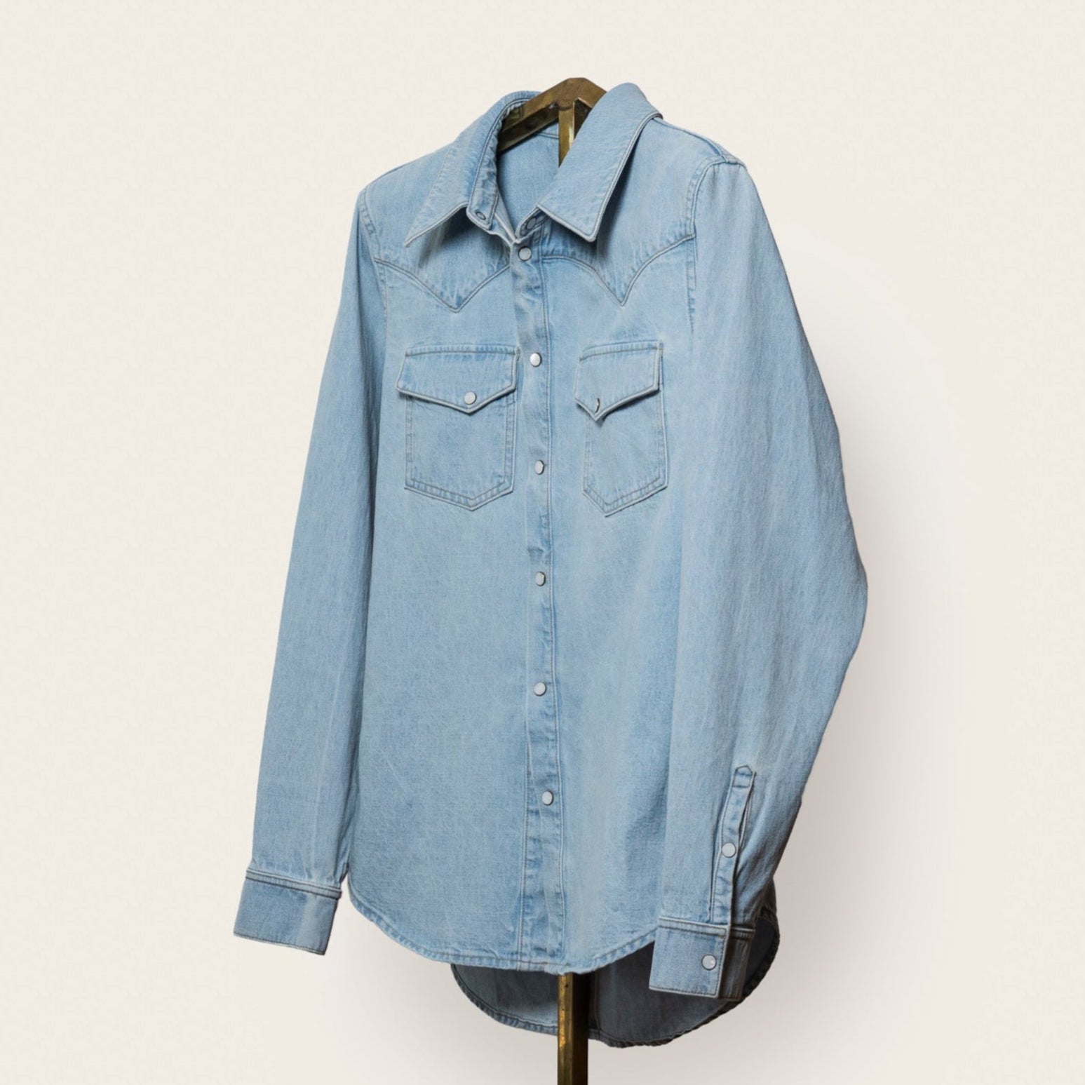 Light blue denim shirt on a hanger against a white background