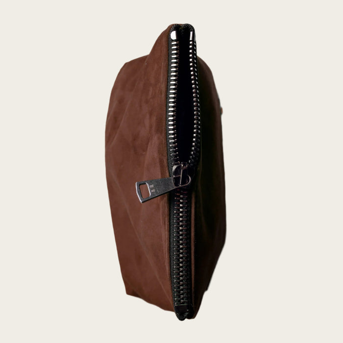 Brown leather pouch with a zipper on a beige background