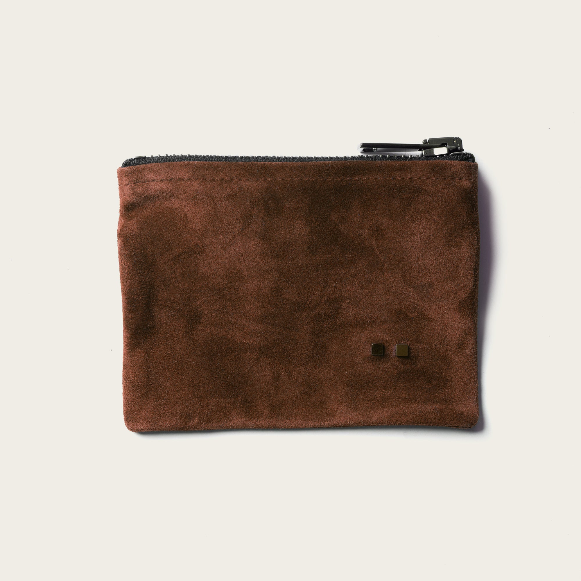 Brown suede pouch with a zipper on a beige background