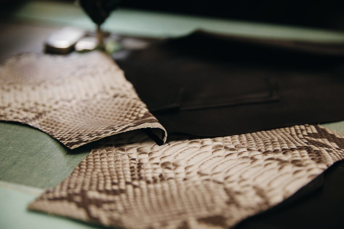 leather and python jacket pieces being sewn on a work table