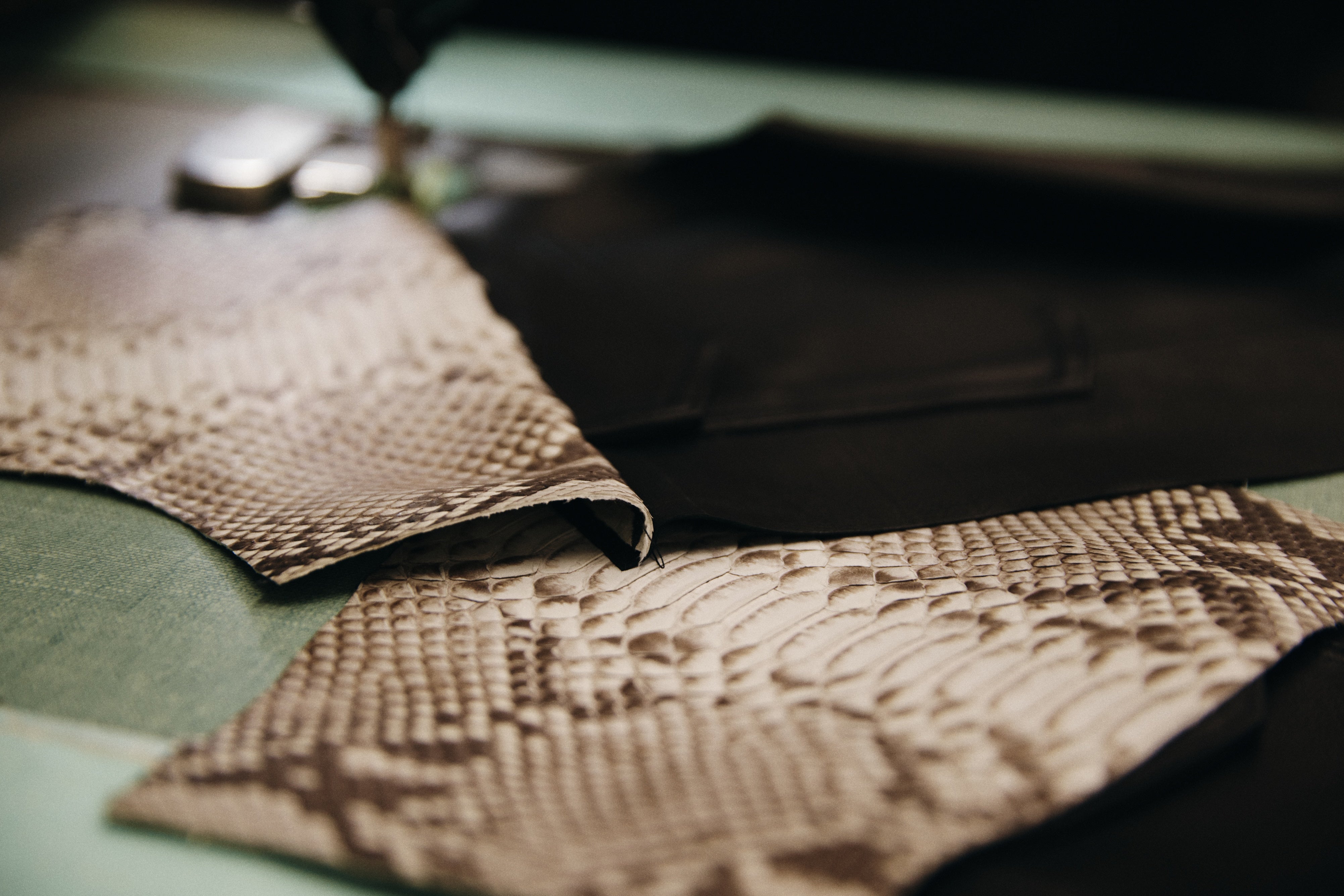 leather and python jacket pieces being sewn on a work table