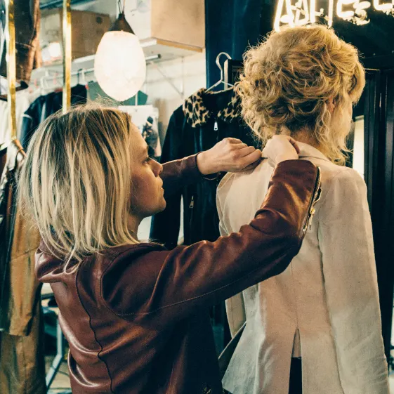 Image of Savannah fitting a woman for a jacket.